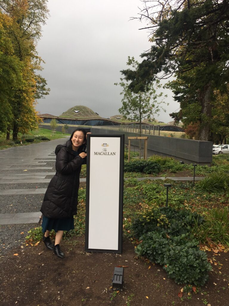 マッカラン蒸溜所にて　
リトルハピネス店主　谷本美香　看板前にて