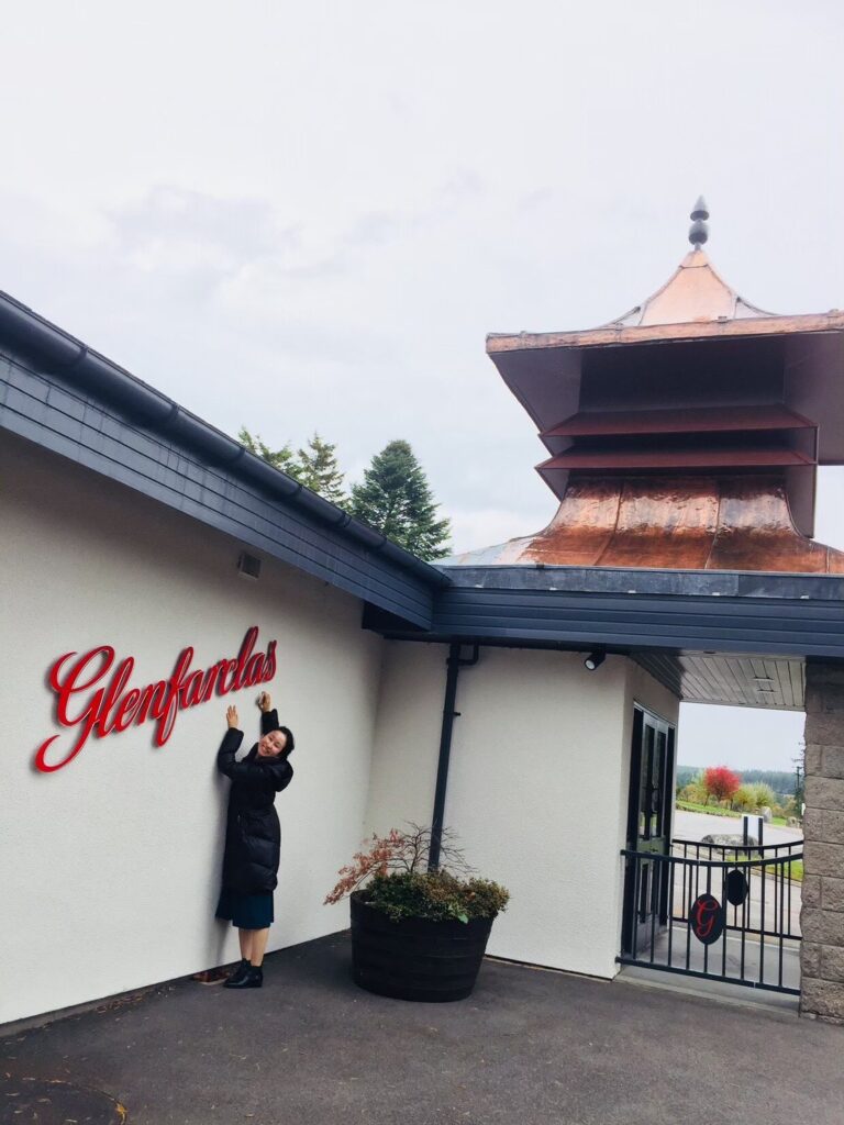 スコットランド・スペイサイドにある憧れのグレンファークラス蒸留所に到着。伝統ある蒸留所の看板の前で、期待に胸を膨らませて記念撮影をする私BarLIttleHappiness 店主 谷本美香