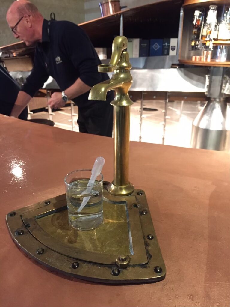 ブレアソール蒸留所のビジターセンター内「マッシュ・タン・バー」で。クライヌリッシュ蒸留所で使われていた巨大な銅製・鋳鉄製の糖化槽を再利用(アップサイクル)した、世界でも類を見ないテイスティングバー。オリジナルのウェッジワイヤー・フィルタープレートの床や、ラウターアームの動きを模したディスプレイなど、ウイスキー製造の歴史を肌で感じられる空間。筆者撮影