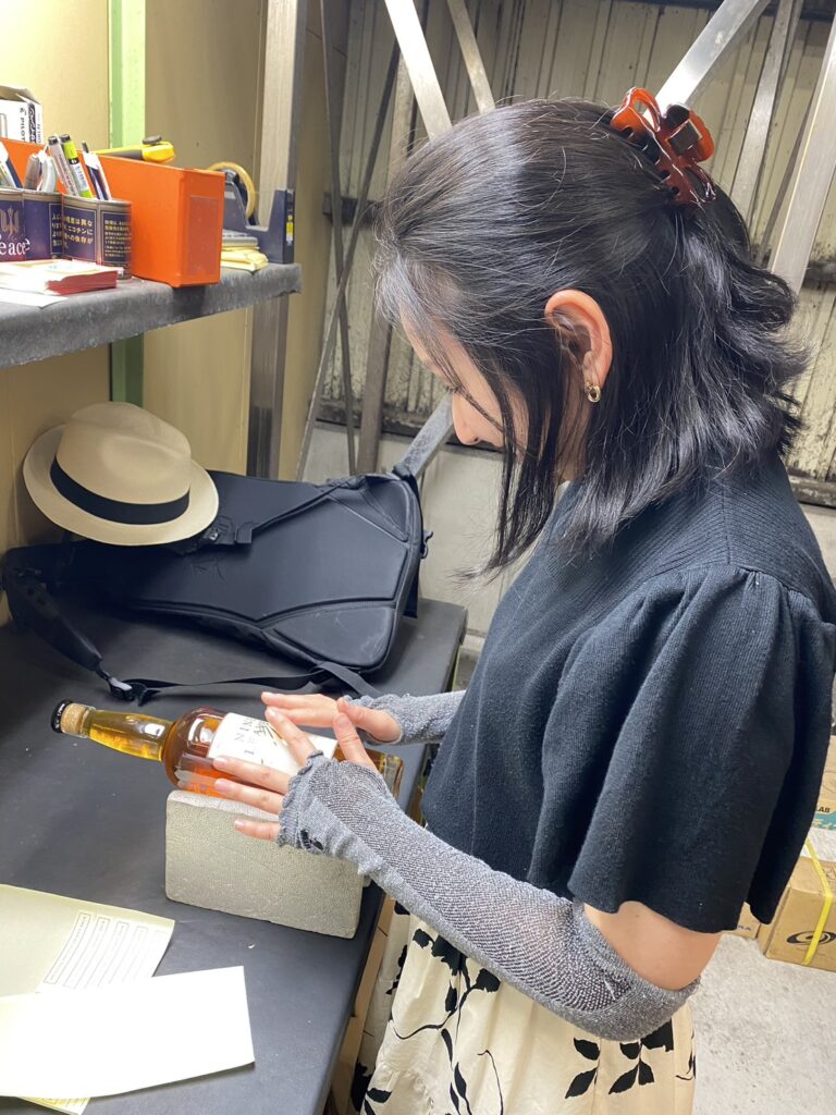 ナインリーブスにて、ボトリング体験。バーリトルハピネス店主・谷本美香が嬉しそうにラベルをはっている。