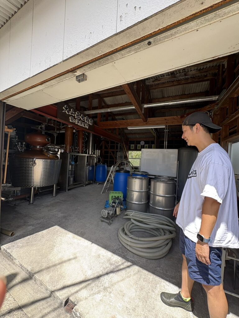 站在存放銅製蘭姆酒蒸餾器的舊車庫前的大山社長